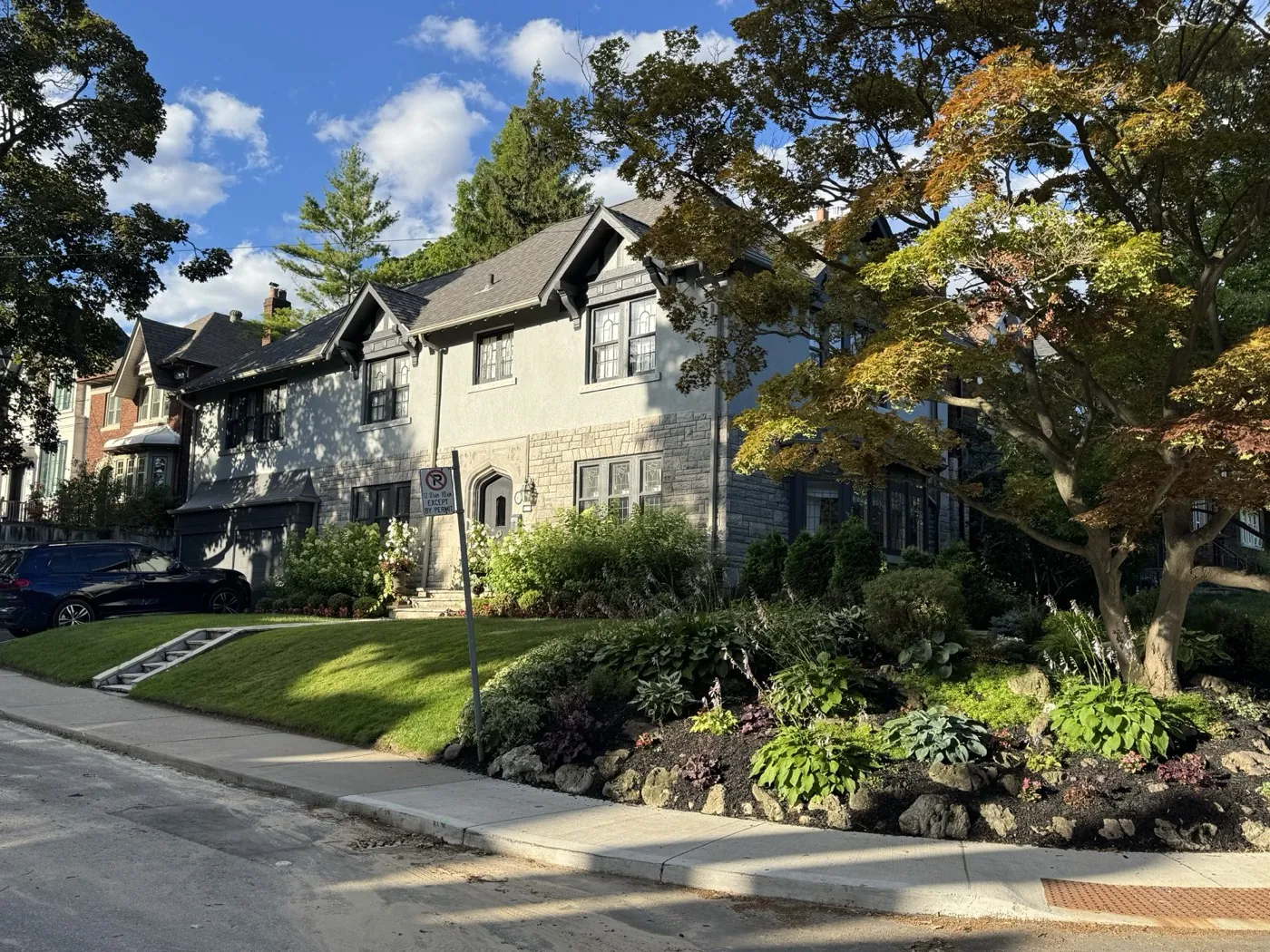 Finished stucco exterior on a Tudor-style Toronto home with stone base and black window frames